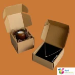 Small kraft e-commerce shipping box with black tissue paper and jewelry items inside, compact packaging solution by Apni Packaging Pakistan